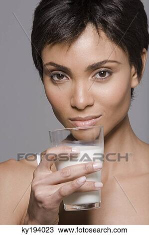 Portrait of a woman holding a glass of milk View Large Photo Image Stock Image - Portrait of a woman holding a glass of milk. Fotosearch