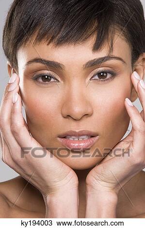 Stock Image - Portrait of a woman with her hands on her chin. Fotosearch