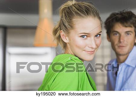 Portrait of a woman smiling with a man in the background View Large Photo Image Stock Image - Portrait of a woman smiling with a man in the background. Fotosearch
