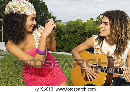 Woman taking a picture of a man playing a guitar View Large Photo Image Stock Image - Woman taking a picture of a man playing a guitar. Fotosearch