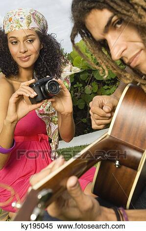 Woman taking a picture of a man playing a guitar View Large Photo Image Stock Photography - Woman taking a picture of a man playing a guitar. Fotosearch