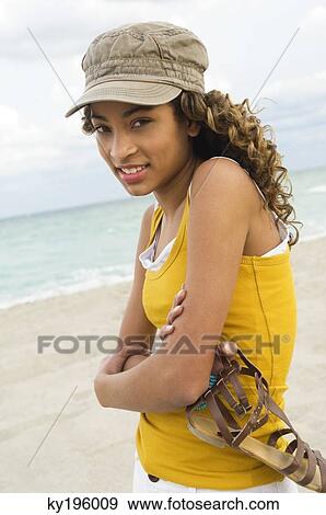 Stock Photo - Girl holding a sandal on the beach. Fotosearch