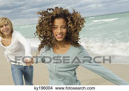 Girl holding hand of a teenage boy on the beach View Large Photo Image Picture - Girl holding hand of a teenage boy on the beach. Fotosearch
