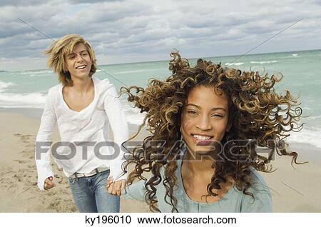 Girl holding hand of a teenage boy on the beach View Large Photo Image Stock Image - Girl holding hand of a teenage boy on the beach. Fotosearch