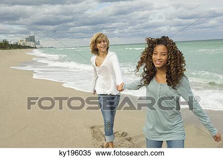 Stock Photography - Girl holding hand of a teenage boy on the beach. Fotosearch
