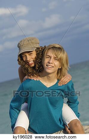 Girl riding piggyback on a teenage boy on the beach View Large Photo Image Stock Photo - Girl riding piggyback on a teenage boy on the beach. Fotosearch