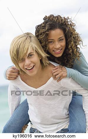 Girl riding piggyback on a teenage boy on the beach View Large Photo Image Stock Photograph - Girl riding piggyback on a teenage boy on the beach. Fotosearch