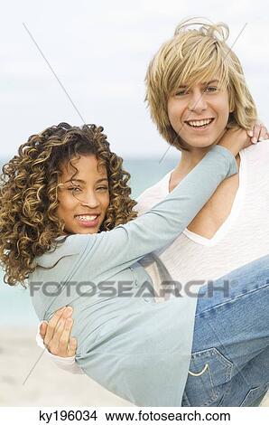 Teenage boy carrying a girl on the beach View Large Photo Image Picture - Teenage boy carrying a girl on the beach. Fotosearch