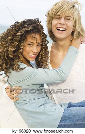 Teenage boy carrying a girl on the beach View Large Photo Image Stock Image - Teenage boy carrying a girl on the beach. Fotosearch