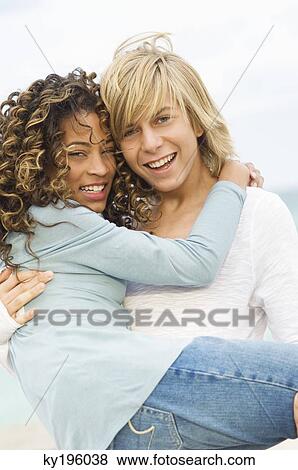 Teenage boy carrying a girl on the beach View Large Photo Image Stock Photo - Teenage boy carrying a girl on the beach. Fotosearch