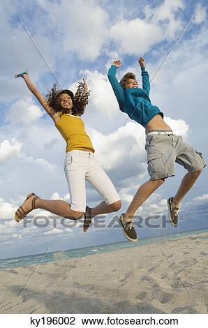 Teenage boy with a girl jumping on the beach View Large Photo Image Stock Image - Teenage boy with a girl jumping on the beach. Fotosearch