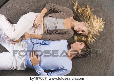 Stock Photo - Couple lying on a round sofa and looking at each other. Fotosearch