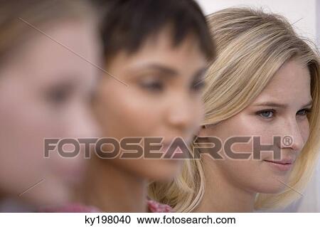 Stock Image - Close-up of three women looking serious. Fotosearch