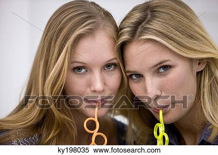 Portrait of two friends sipping drink with drinking straws View Large Photo Image Stock Photography - Portrait of two friends sipping drink with drinking straws. Fotosearch