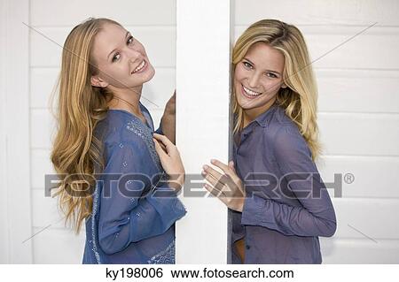Stock Photograph - Two women leaning against a column and smiling. Fotosearch