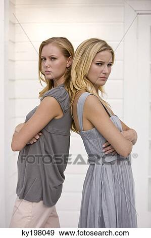 Stock Photo - Two women standing back to back and looking serious. Fotosearch