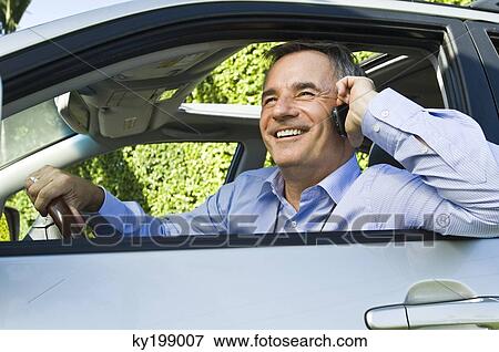 Stock Photo - Man in a car and talking on a mobile phone. Fotosearch