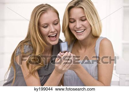 Two women reading message on a mobile phone View Large Photo Image Picture - Two women reading message on a mobile phone. Fotosearch