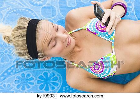 Woman lying on a sheet and text messaging on a mobile phone View Large Photo Image Stock Image - Woman lying on a sheet and text messaging on a mobile phone. Fotosearch