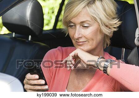Stock Photo - Woman sitting in a car and text messaging. Fotosearch