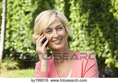 Woman talking on a mobile phone and smiling View Large Photo Image Stock Photograph - Woman talking on a mobile phone and smiling. Fotosearch