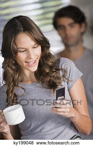 Woman text messaging on a mobile phone and smiling View Large Photo Image Stock Photo - Woman text messaging on a mobile phone and smiling. Fotosearch