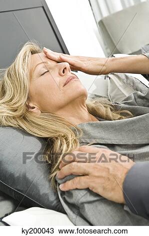 Stock Image - Man touching the forehead of an ill woman. Fotosearch
