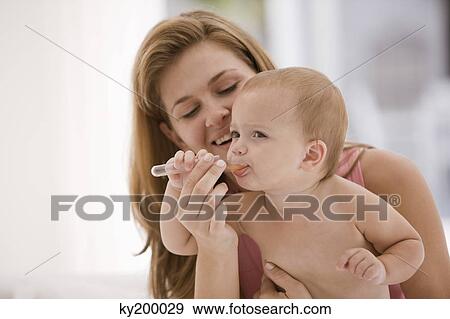 Woman giving medicine to her daughter View Large Photo Image Stock Photo - Woman giving medicine to her daughter. Fotosearch