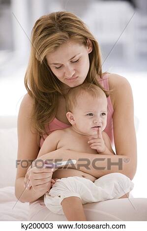 Woman looking at a pregnancy test stick with a her daughter sitting on her lap View Large Photo Image Stock Image - Woman looking at a pregnancy test stick with a her daughter sitting on her lap. Fotosearch