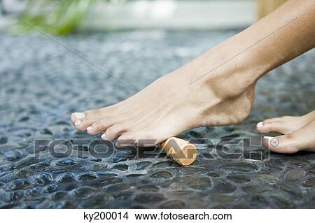 Woman massaging her foot with a foot roller View Large Photo Image Picture - Woman massaging her foot with a foot roller. Fotosearch