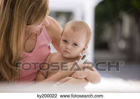 Woman taking her daughter's temperature with a thermometer View Large Photo Image Stock Image - Woman taking her daughter's temperature with a thermometer. Fotosearch