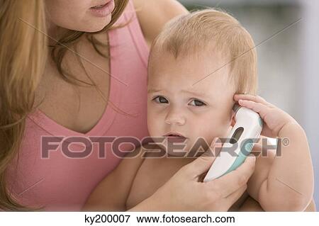 Woman taking her daughter's temperature with a thermometer View Large Photo Image Stock Photo - Woman taking her daughter's temperature with a thermometer. Fotosearch