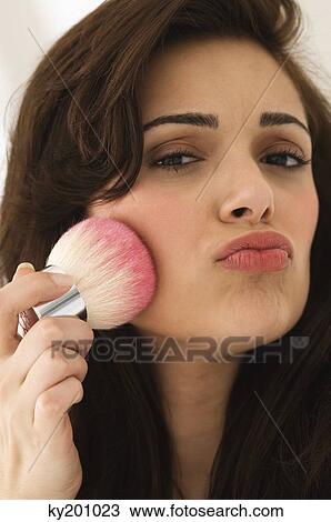 Portrait of a woman applying blusher on her face View Large Photo Image Stock Image - Portrait of a woman applying blusher on her face. Fotosearch