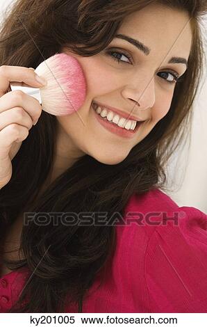Portrait of a woman applying blusher on her face View Large Photo Image Stock Photography - Portrait of a woman applying blusher on her face. Fotosearch