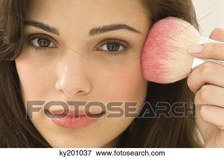 Woman applying blusher on her face View Large Photo Image Stock Photo - Woman applying blusher on her face. Fotosearch