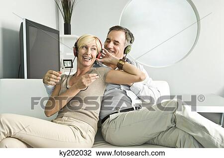 Couple listening to music with headphones and smiling View Large Photo Image Stock Image - Couple listening to music with headphones and smiling. Fotosearch