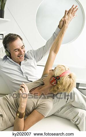 Stock Photo - Couple listening to music with headphones and smiling. Fotosearch