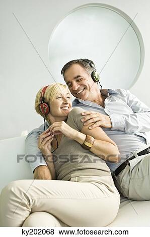 Couple listening to music with headphones and smiling View Large Photo Image Stock Photo - Couple listening to music with headphones and smiling. Fotosearch