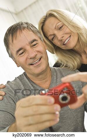 Couple looking at a digital camera View Large Photo Image Stock Photo - Couple looking at a digital camera. Fotosearch