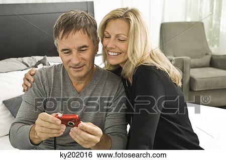 Couple looking at a digital camera View Large Photo Image Stock Photograph - Couple looking at a digital camera. Fotosearch