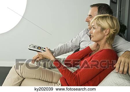 Couple watching television on a couch View Large Photo Image Stock Photo - Couple watching television on a couch. Fotosearch
