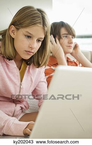 Girl working on a laptop and boy listening headphones View Large Photo Image Stock Image - Girl working on a laptop and boy listening headphones. Fotosearch