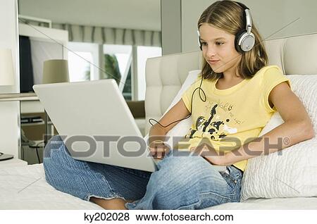 Stock Photo - Girl working on a laptop and listening to headphones. Fotosearch