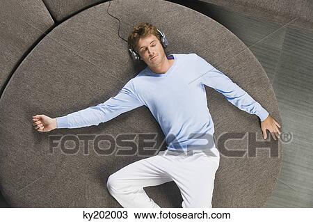 Man lying on a round sofa and listening to music View Large Photo Image Stock Image - Man lying on a round sofa and listening to music. Fotosearch