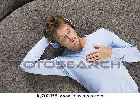 Man lying on a round sofa and listening to music View Large Photo Image Stock Photo - Man lying on a round sofa and listening to music. Fotosearch
