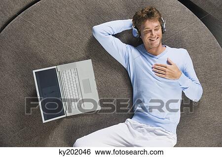 Man lying on a round sofa and listening to music View Large Photo Image Stock Photograph - Man lying on a round sofa and listening to music. Fotosearch