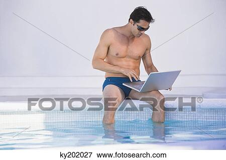 Man using a laptop at the poolside View Large Photo Image Stock Photo - Man using a laptop at the poolside. Fotosearch