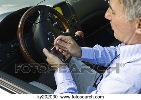 Man using a personal data assistant in a car View Large Photo Image Stock Image - Man using a personal data assistant in a car. Fotosearch