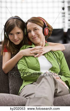 Woman listening to music and her granddaughter hugging from behind View Large Photo Image Stock Image - Woman listening to music and her granddaughter hugging from behind. Fotosearch