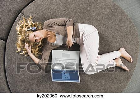 Woman lying on a round sofa and listening to music View Large Photo Image Stock Image - Woman lying on a round sofa and listening to music. Fotosearch